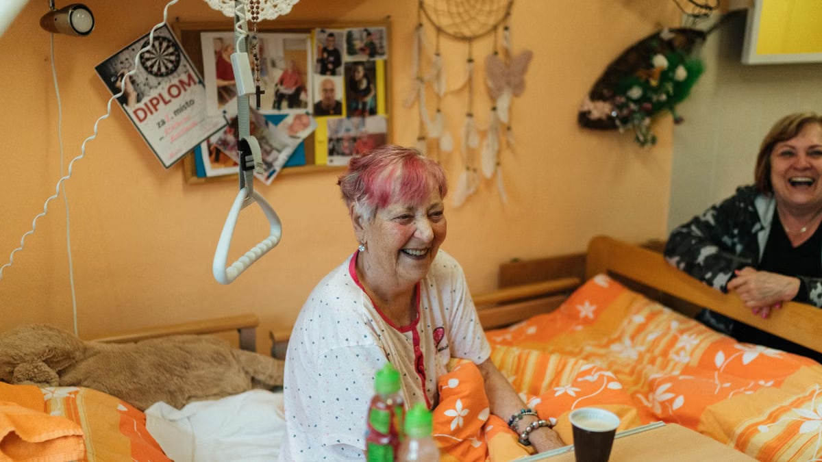 Cheerful elderly women sharing a light moment in a cozy hospital room.
