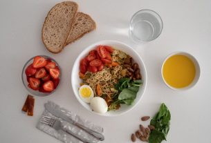 A balanced meal featuring a variety of healthy ingredients including noodles, eggs, almonds, strawberries, and fresh vegetables.